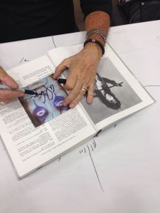 The hands of Alice Cooper signing my book and CD cover